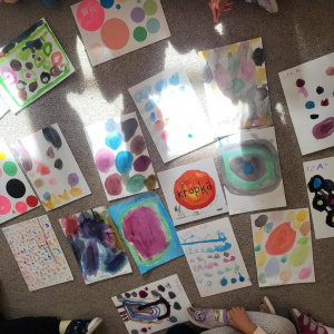 Zdjęcie przedstawia prace plastyczne z kolorowymi kropkami, na środku leży książki "Kropka"