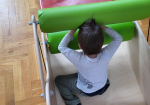 chłopiec w szarym ubraniu przeciska się przez maglownice sensoryczną