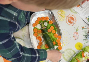 Chłopiec układający warzywa na talerzu