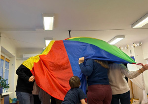 Grupa ludzi schowana pod kolorową chustą animacyjną