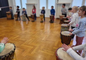Grupa dzieci stojąca przy bębnach afrykańskich