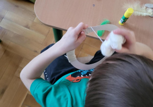 Chłopiec owijający papierowy krążek białą włóćzką