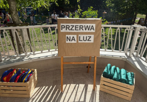 Stanowisko „Przerwa na luz” przygotowane podczas rodzinnego pikniku w przedszkolu z workami do zabaw i relaksu, a w tle uczestnicy wydarzenia w ogrodzie.